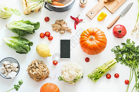 秋季烹饪平板躺智能手机与空白屏幕各种季节秋季蔬菜配料南瓜白色桌背景,顶部视图舒适的家秋收食物博客图片