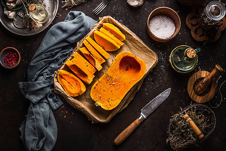 奶油南瓜半烤盘上用草药香料刀器皿黑暗的厨房桌子背景上烹饪准备的风景健康的季节食物图片
