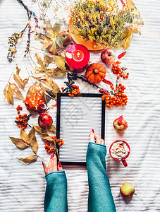 女的手白色的毯子背景上空白的字母板,秋天的枝叶,燃烧的蜡烛,南瓜,红色的卡布奇诺杯秋天的装饰的风景图片