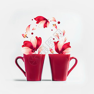 两个红色的杯子,红色的白色飞花花瓣的花站白色的背景上创造夫妻的浪漫的假日布局图片