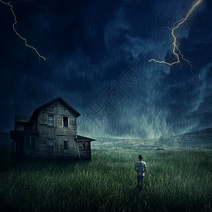 幽灵般的风景,就像个小男孩草地上散步样,看着黑暗的暴风雨天空下的鬼屋背景图片