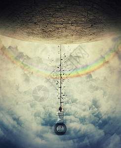小男孩停彩虹上空云层中的轮胎秋千上,避免重力乐趣自由的图片