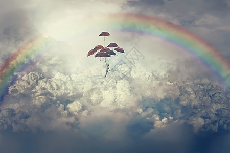 想象中的景色,个轻的男孩举着很多雨伞,云层上方飞翔天空彩虹下的人生旅程图片