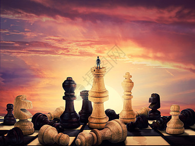 成功的男孩站块棋子上,迎接地平线上的日出巨大的棋子散落老式棋盘上商业愿望自由领导理念的象征背景图片