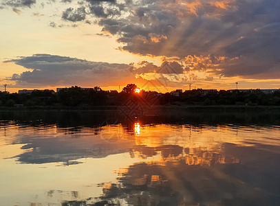 美妙的日落城市地平线上,个寂静的夏季傍晚,平静的湖水上倒影图片