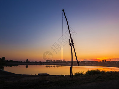田园诗般的乡村景象与个古老的水井流行的称为鹳井老村庄的摩尔多瓦,也扫井沙多夫平静的日落天空反射湖上图片
