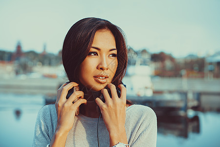 轻的亚洲妇女戴着耳机城市背景上的肖像轻的亚洲女人图片