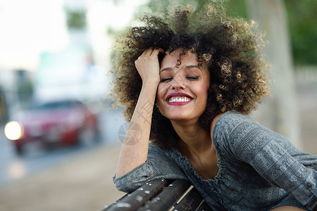 轻的黑人妇女,留着AFRO发型,城市背景下微笑穿着休闲衣服的混合女孩图片
