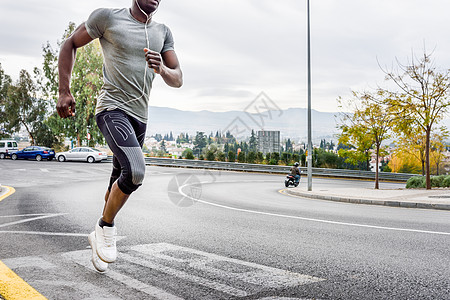 黑人城市道路上跑步,用白色耳机听音乐轻的男锻炼与城市替罪羊的背景图片