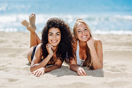 两个轻的女人穿着泳衣热带两个轻的女人穿着泳装热带海滩上趣的白种人阿拉伯女穿着黑白泳衣躺沙滩上背景图片