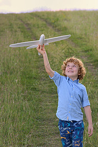 小男孩田野上着个木制的飞机模型图片