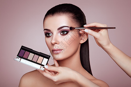 化妆师应用眼影化妆师应用眼影漂亮的女人脸完美的妆容化妆细节美丽的女孩完美的皮肤指甲指甲眼影调色板图片