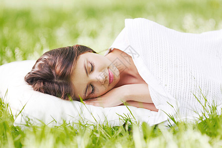 轻的女人睡清新的春草里的白色枕头上女人睡草地上图片