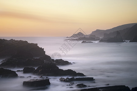 惊人的长曝光景观图像的海洋岩石上,充满活力的日落图片
