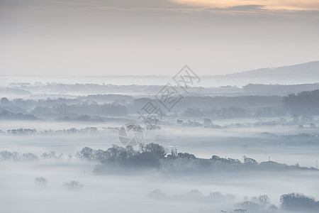 令人惊叹的雾状英国乡村景观日出冬季美丽的雾状英国乡村景观日出冬天,层层滚动田野背景图片