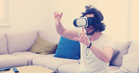 快乐的男人家里用虚拟现实的VR耳机眼镜获得体验背景图片