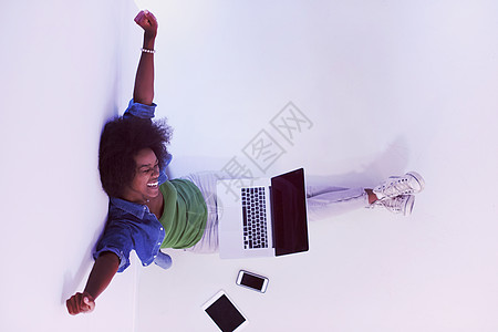 幸福的轻非洲裔美国妇女坐地板上的笔记本电脑顶部视图的肖像背景图片