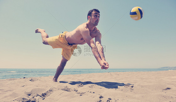 男子沙滩排球比赛运动员跳热沙上图片
