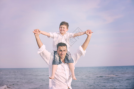 快乐的轻父亲儿子日落时享受海滩上的时光,代表着健康的家庭支持理念图片