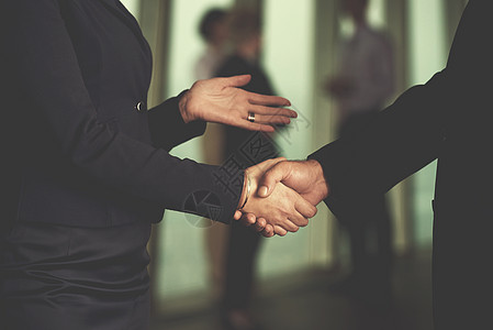 商务握手与高级商务人员的伙伴关系理念,现代办公室内部进行握手达成协议背景