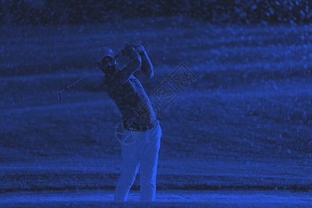高尔夫球手日落时击中了个沙坑高尔夫球手高尔夫球场沙坑中射出球,背景色调为美丽的日落图片