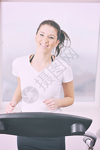 轻女子运动俱乐部跑步时锻炼身体锻炼健身俱乐部的妇女锻炼跑步轨道机上图片