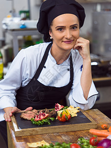 酒店餐厅厨房的女厨师准备牛排蔬菜装饰女厨师准备牛排图片