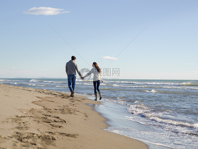 轻的夫妇秋天阳光明媚的日子里海滩上散步拥抱爱的轻夫妇秋天阳光明媚