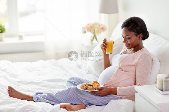 怀孕,人饮食快乐怀孕的非裔美国妇女喝橙汁与糕点床上家孕妇床上喝橙汁糕点图片