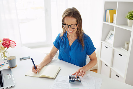 商业,财务会计中妇女与计算器计数写作笔记本办公室办公室里计算器笔记本的女人图片