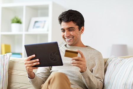 技术,人网上购物的微笑的人与平板电脑信用卡家里微笑的男人家里平板电脑信用卡图片