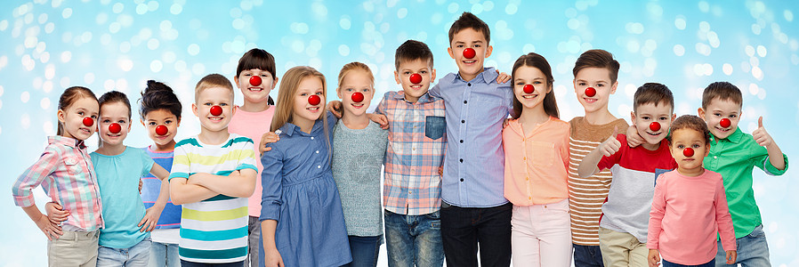 红鼻子日,慈善童的快乐的微笑孩子与小丑鼻子拥抱灯光蓝色的背景快乐的孩子红鼻子的日子拥抱图片