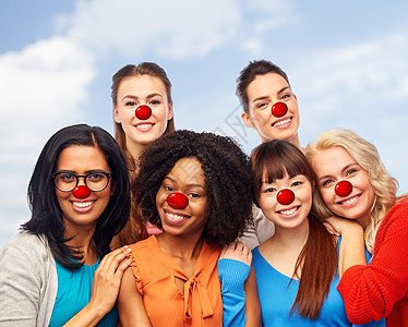 红鼻子日,多样人的国际集快乐微笑同的妇女与小丑鼻子拥抱天空背景红鼻子日的国际快乐女体图片