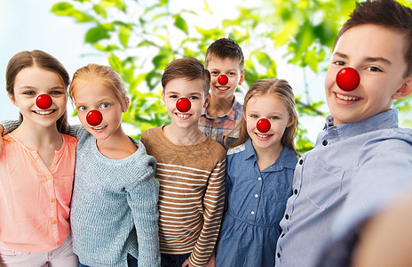 红鼻子日,慈善童的快乐的孩子与小丑鼻子绿色的自然背景上自拍快乐的孩子红鼻子日自拍图片