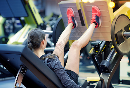 健身,运动,健美,锻炼人的轻妇女健身房的腿部压力机上弯曲肌肉妇女健身房的腿部压力机上弯曲肌肉图片