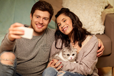 休闲,技术人的快乐的夫妇与猫家里用智能手机自拍幸福的夫妇家里用智能手机自拍图片