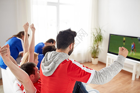 体育人娱乐活动快乐的朋友球迷电视上看足球比赛,并家里庆祝胜利足球迷家看电视上的足球比赛图片