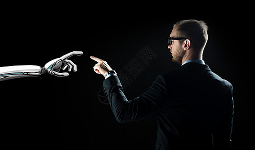 商业,未来技术人工智能商人机器人移交黑色背景机器人人类的手闪过黑色的光图片