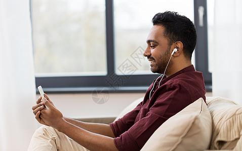技术,休闲人的快乐的人耳机与智能手机听音乐家戴耳机的人智能手机上听音乐图片