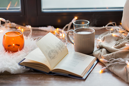 潮湿舒适的家庭书,咖啡热巧克力蜡烛与花环窗台上窗台上的书咖啡热巧克力图片