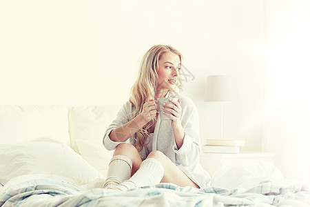 早上,休闲人们的快乐的轻女人家里的卧室床上喝咖啡茶快乐的女人家里床上喝咖啡图片