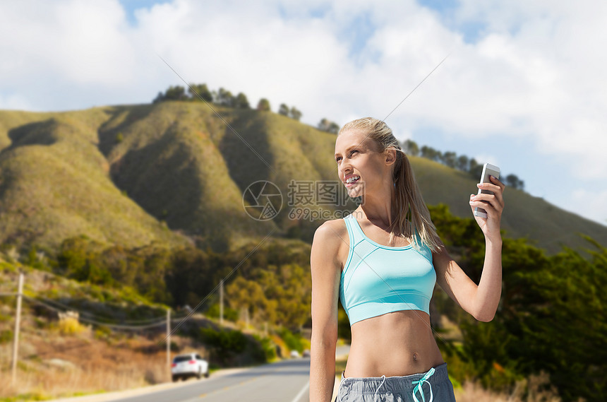 健身,运动技术微笑的轻妇女与智能手机锻炼大苏尔山道路背景加利福尼亚智能手机的女人山上运动智能手机图片