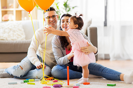 家庭,假期人的快乐的母亲,父亲小女儿家里的生日聚会上伸手气球女婴生日聚会上伸手气球女婴生日聚会上图片