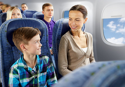 旅行,旅游家庭快乐的母亲儿子坐飞机上,舷窗背景下交谈快乐的母子乘飞机旅行快乐的母子乘飞机旅行图片