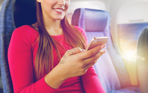 旅行,旅游,技术航空飞行的接近快乐的轻妇女坐飞机上与智能手机舷窗背景用智能手机坐飞机上的女人用智能手图片