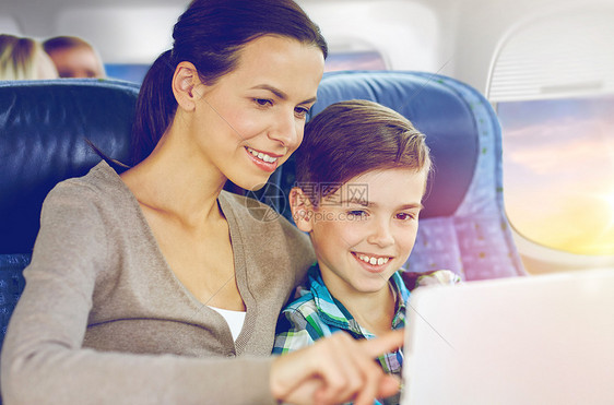 旅行,旅游,家庭技术快乐的母亲儿子与平板电脑电脑坐飞机上的舷窗背景快乐的家庭与平板电脑坐飞机上快乐的家庭与图片