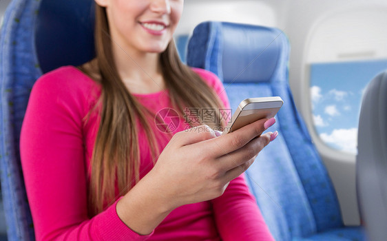 坐飞机上的女人用智能手机图片