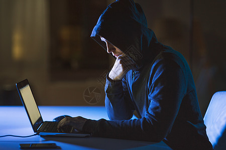 网络犯罪,黑客技术犯罪男黑客黑暗的房间用笔记本电脑进行网络攻击黑客用笔记本电脑进行网络攻击黑客用笔记本电脑图片