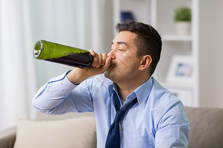 酒精中,酒精成瘾人的男酒精饮用红酒瓶颈家里男酗酒者家瓶子里喝葡萄酒男酗酒者家瓶子里喝葡萄酒背景图片