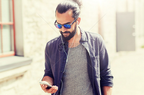 人,音乐,技术,休闲生活方式男人带着耳机智能手机城市里散步带着耳机智能手机的男人城市里散步带着耳机智能手机图片